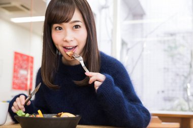 Güzel genç bir kadın Japon restoranında öğle yemeği yiyor.