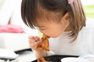 Asyalı çocuk kızarmış tavuk yiyor. Yakından. 