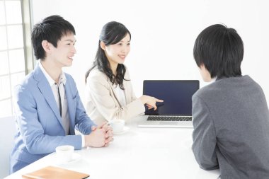 Genç Japon iş adamları ofiste dizüstü bilgisayarla çalışıyorlar.