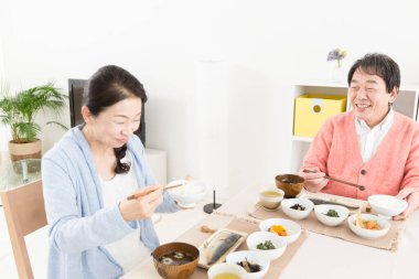 Üst düzey Asyalı çift mutfakta yemek yiyor.