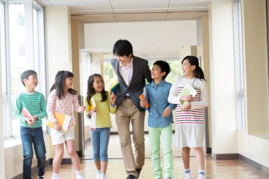 Öğretmenli bir grup Japon çocuk okul koridorunda yürüyor. 