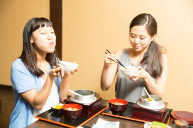 Güzel Asyalı kadınlar restoranda geleneksel Japon yemekleri yiyorlar.