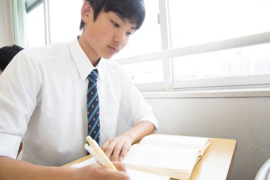 Asyalı öğrenci sınıfta okuyor.