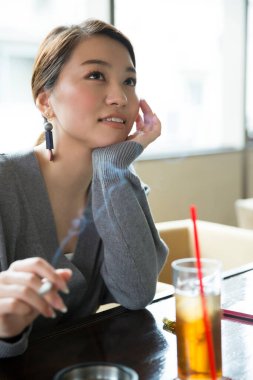 Kadın içeride düşünüyor ve sigara içiyor.