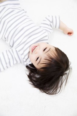 Asyalı çocuk yatakta yatıyor.