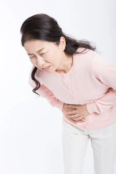 孤立した背景に胃の痛みを持つシニアアジアの女性 — ストック写真