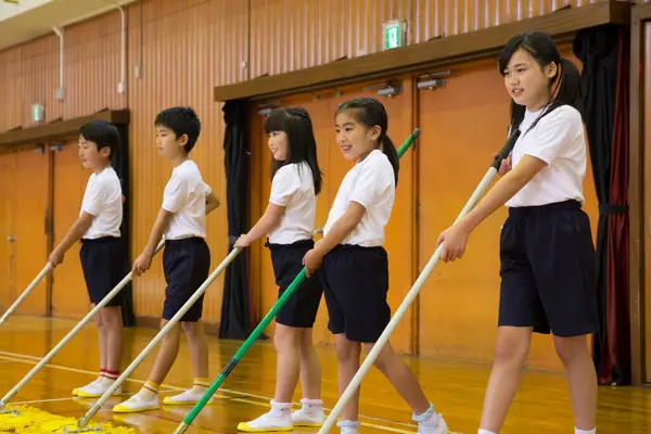 group of children in a uniform cleaning sport gym in school