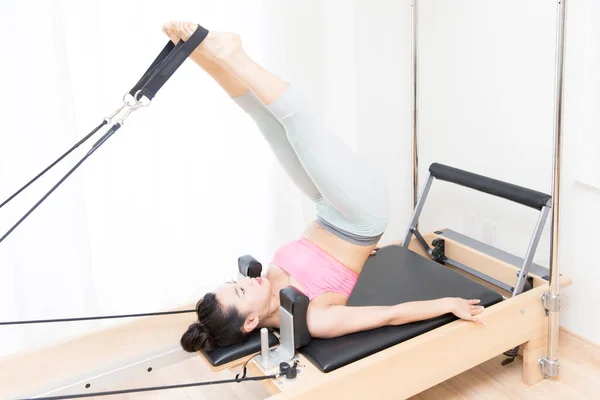 Stock image sporty Japanese woman in sportswear training with reformer indoors