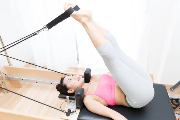 stock image sporty Japanese woman in sportswear training with reformer indoors