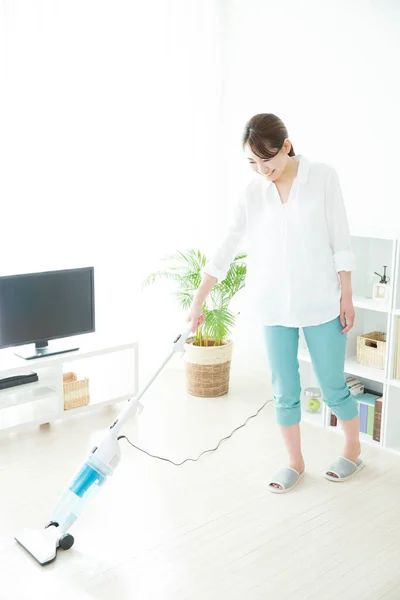 若いアジアの女性は家事をする 掃除機のリビングルームを掃除する日本の主婦 — ストック写真