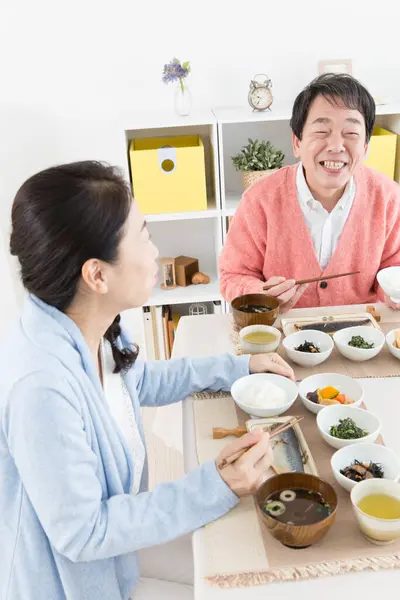 キッチンで食事を持っているシニアアアジアのカップル — ストック写真