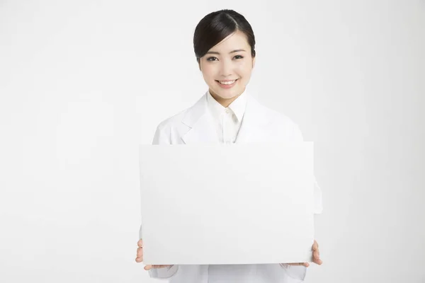 白い背景に隔離された空白の旗を示す若いアジアの女性の医者 — ストック写真