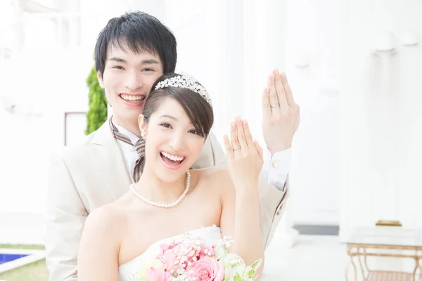 カメラで結婚指輪と笑顔を示す美しい若い結婚式のカップル — ストック写真