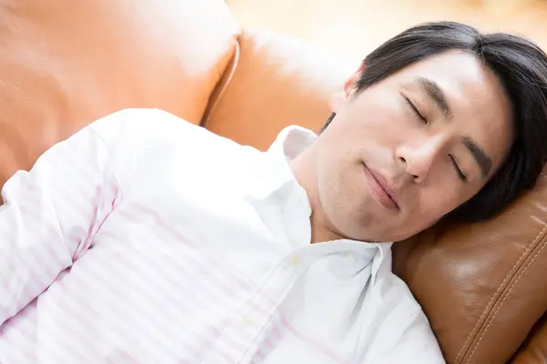 asian man lying on a sofa and sleeping