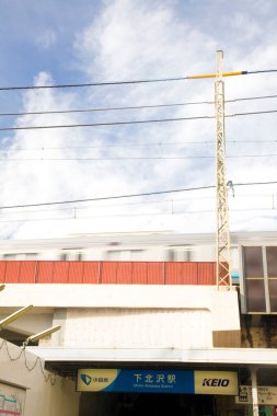 Mavi gökyüzünün altından geçen tren ve yukarıda beyaz bulutlar