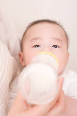 Anne, tatlı Asyalı bebeği şişeden besliyor.