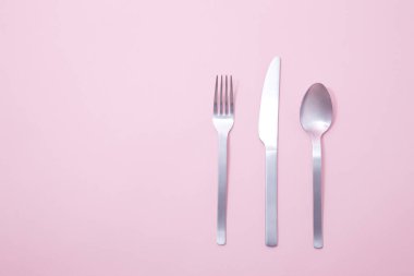 bıçak, kaşık ve çatal pembe arka planda.