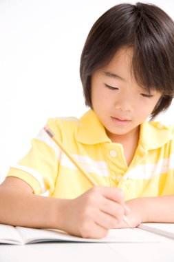 Asyalı çocuk beyaz arka plan üzerinde çalışıyor.