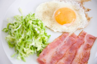 Kızarmış yumurta ve salata yapraklı pastırma. 