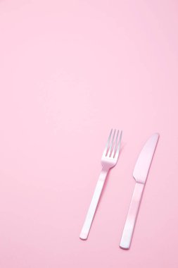 Bıçak ve çatal pembe arka planda. Üst Manzara. düz yat.