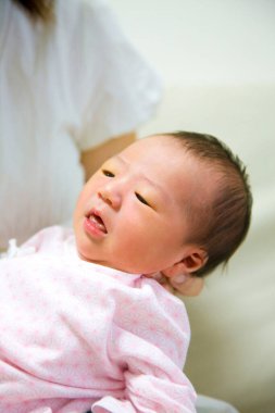 Annesi olan Asyalı yeni doğmuş bir kız bebek. 