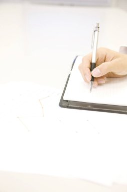 Kapalı - Ofisteki deftere kalem ve yazı tutan işadamının eli.
