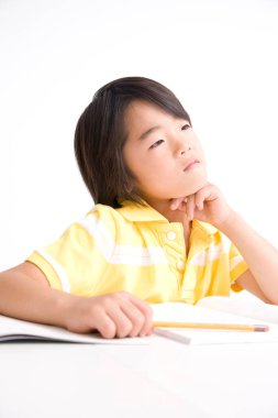 Asyalı çocuk beyaz arka plan üzerinde çalışıyor.