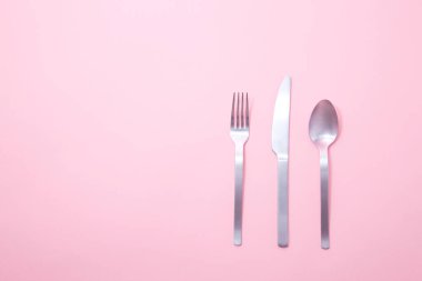 Çatal, bıçak ve kaşık pembe arka planda. Üst görünüm, düz görünüm, kopyalama alanı.