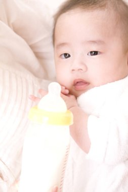 Anne, tatlı Asyalı bebeği şişeden besliyor.