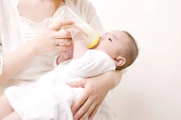 mother feeding cute asian newborn baby from bottle