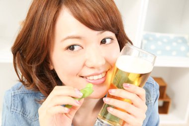 Neşeli Japon kadın evde bira içiyor.