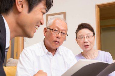 Üç yetişkin birlikte belgeleri tartışıyor.