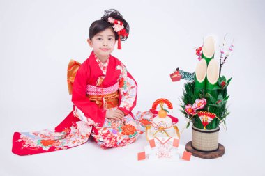 Beyaz stüdyo arka planında geleneksel kırmızı kimono giyen güzel Japon kızın portresi.