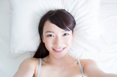 Kadın yatakta selfie çekiyor. 