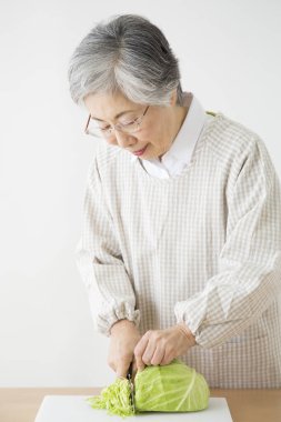 Yaşlı kadın sebze salatası hazırlıyor lahana doğruyor. 