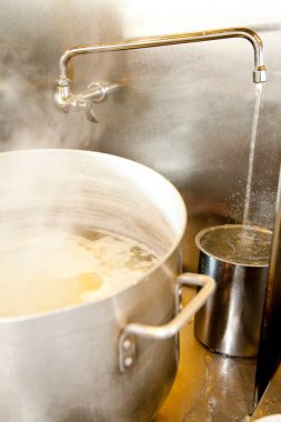 Büyük tencere, metal musluğun altında kaynar su.