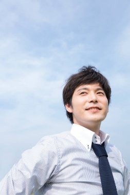 Gökyüzü arka planında beyaz gömlekli genç iş adamı 