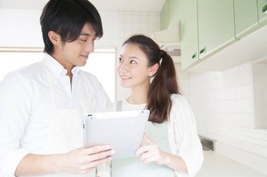 Mutfakta tablet bilgisayarı olan genç çift.