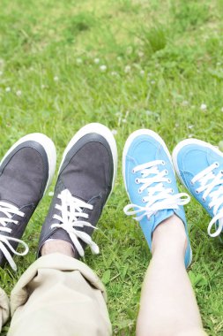Erkek ve kadın çimlerin üzerinde spor ayakkabı giyerler. 
