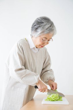Yaşlı kadın sebze salatası hazırlıyor lahana doğruyor. 