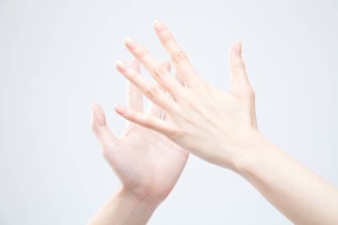 Beyaz arka planda el hareketi yapan kadınların yakın çekimi. 