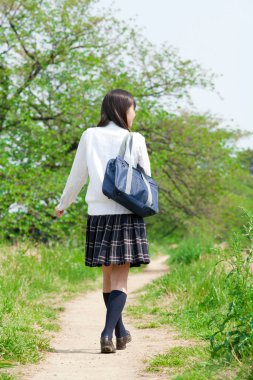 Genç bir kadın parkta yürüyor.