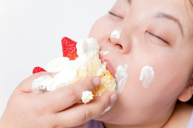 Beyaz arka planda pasta yiyen şişman Japon kadının stüdyo portresi