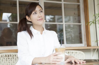 Kafede kahve içen Asyalı bir kadının portresi.