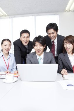 Dizüstü bilgisayarla çalışan bir grup genç Japon iş adamı.