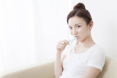 Banyoda diş fırçalayan Asyalı kadın.