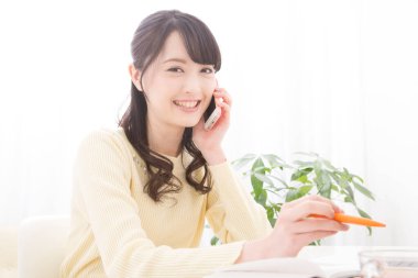 Akıllı telefondan konuşan gülümseyen Asyalı kadın. Toplantı programına bakıyorum. randevu alınıyor