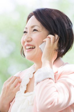 Dışarıda cep telefonuyla konuşan Asyalı kadın.