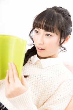 Şaşırmış kadın evde kitap okuyor. 