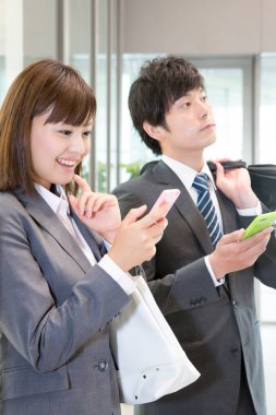 İş kadını ve işadamı ofiste akıllı telefon kullanıyor. 